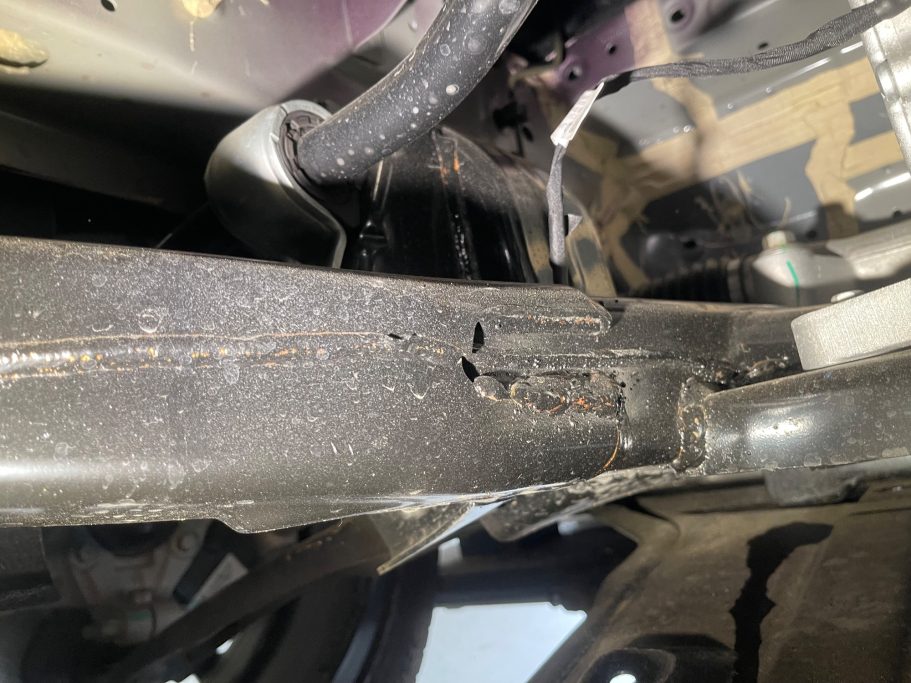 Detailaufnahme eines Fahrzeugrahmens mit Schmutz und Gebrauchsspuren.
