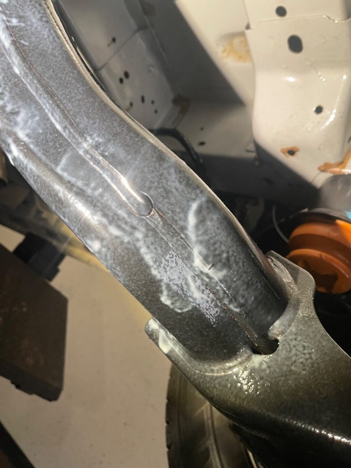 Nahaufnahme eines Metallrahmens mit Kratzern und einer orangefarbenen Komponente.